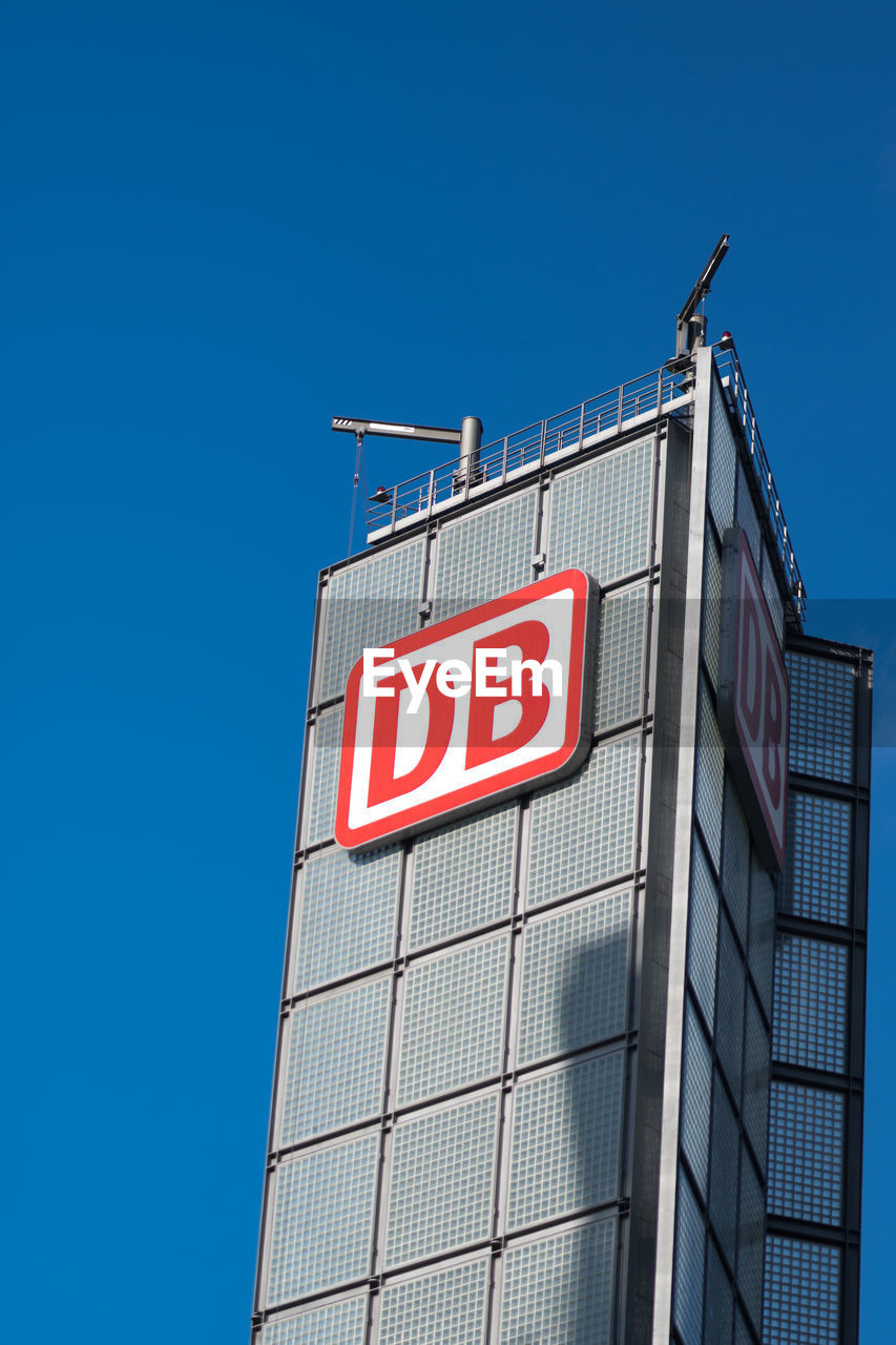 LOW ANGLE VIEW OF TEXT ON MODERN BUILDING AGAINST CLEAR BLUE SKY