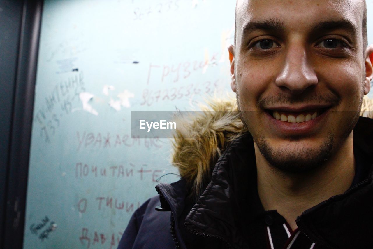 Portrait of smiling young man against whiteboard in classroom