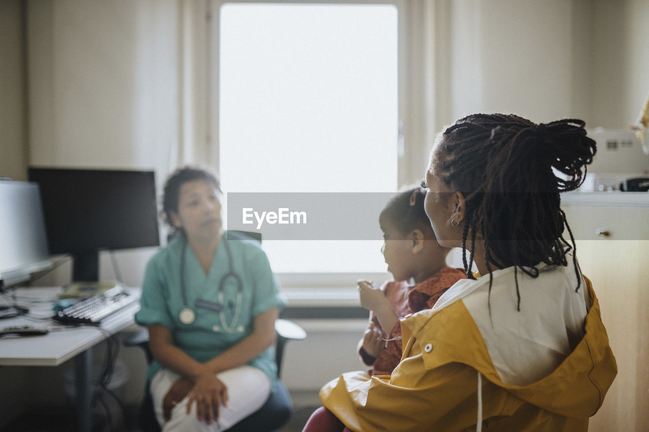 Woman with daughter visiting female pediatric in clinic