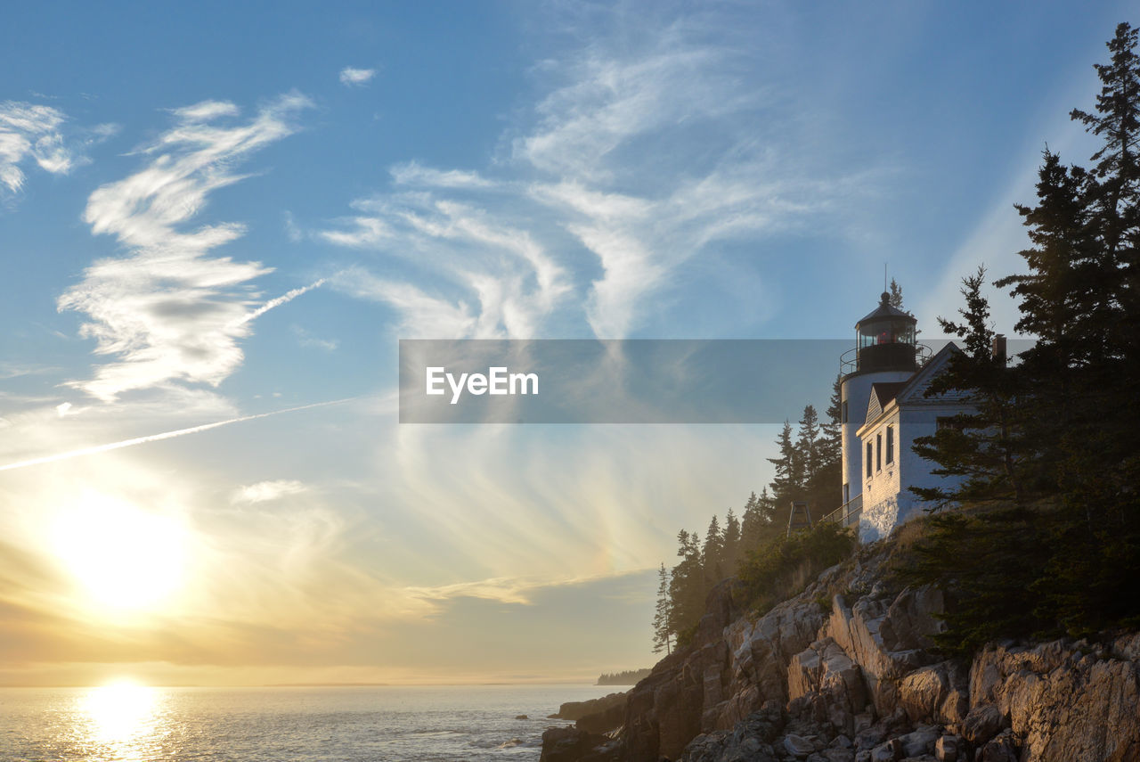 Lighthouse amidst sea and buildings against sky