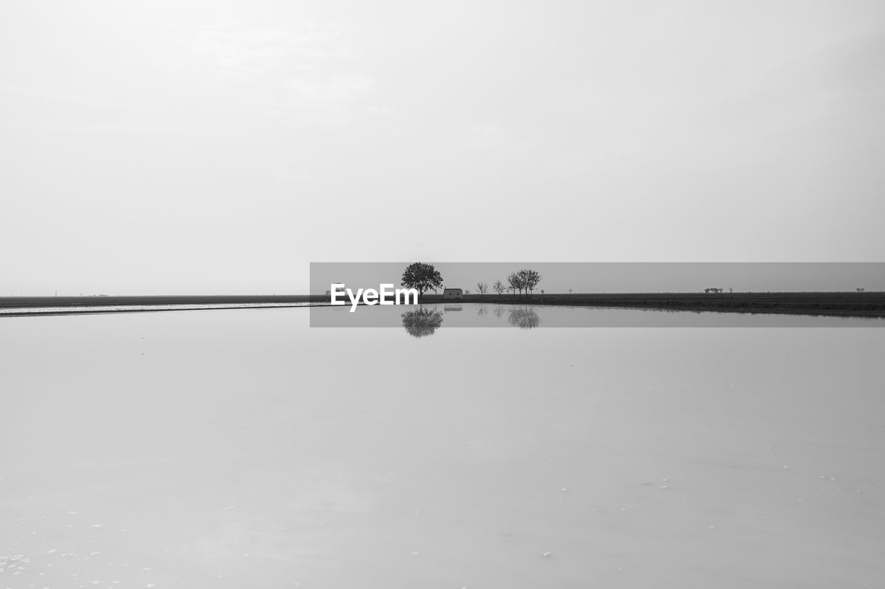 HELICOPTER OVER LAKE AGAINST SKY