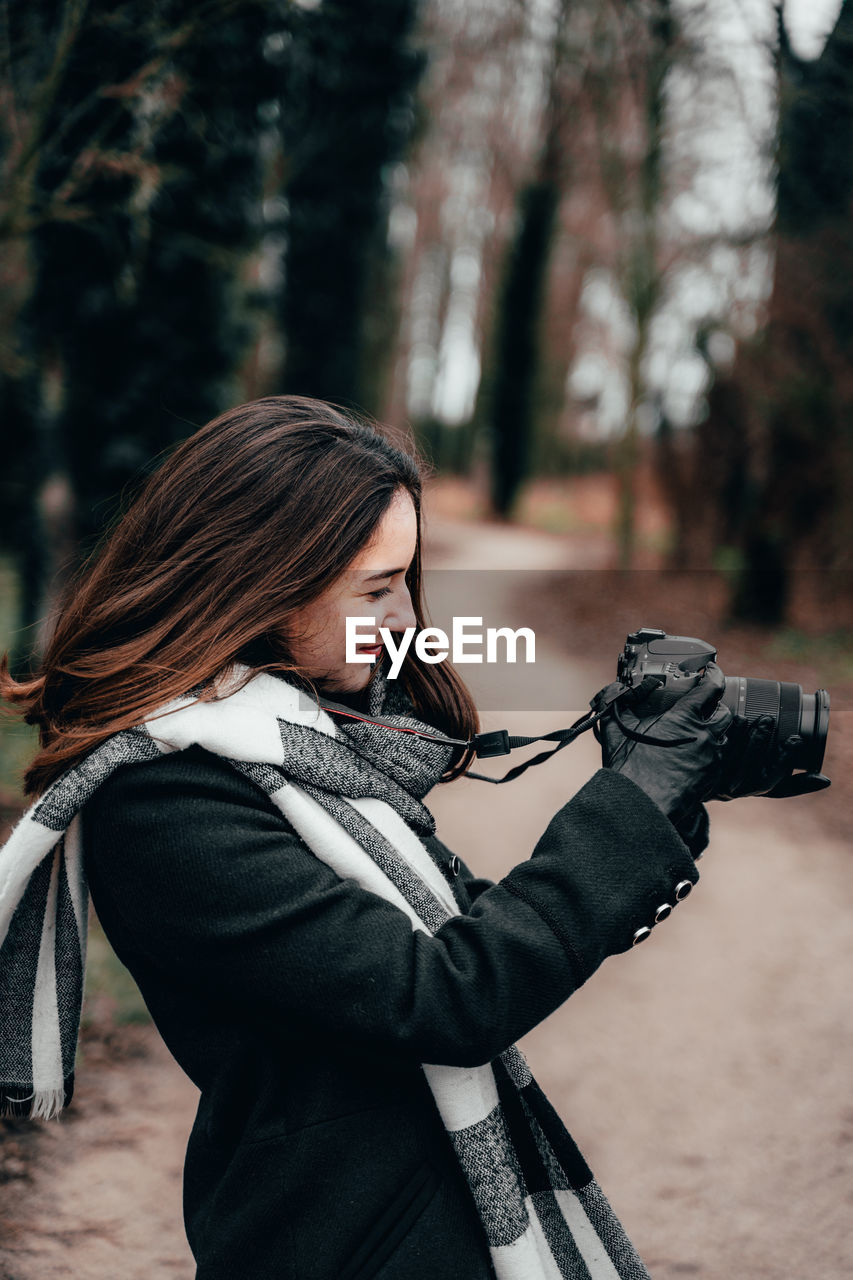 Young woman photographing with camera in forest