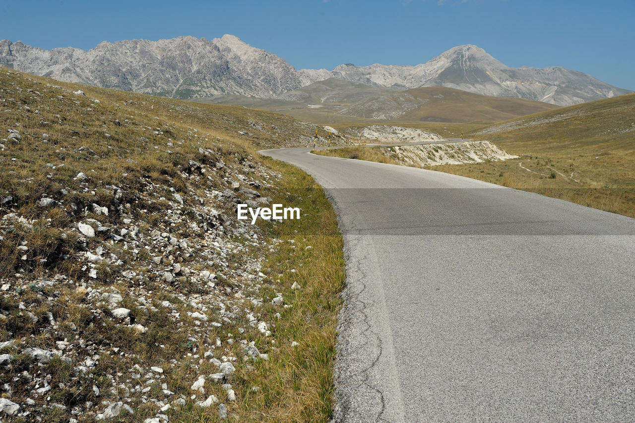 Scenic view of road by mountains against sky