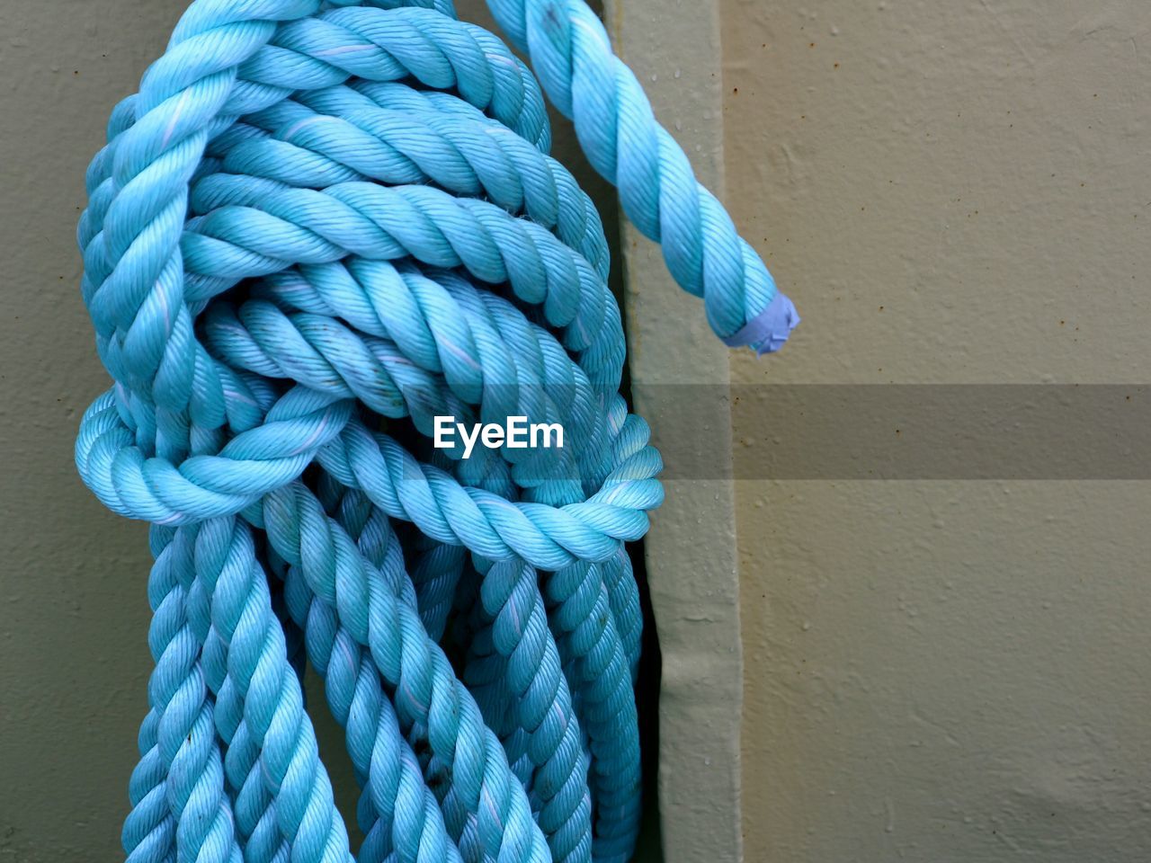 Coil of light blue rope against grey background