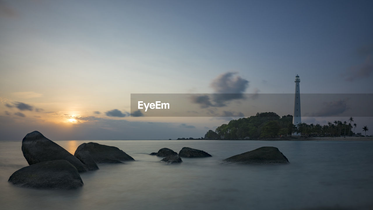 ROCKS IN SEA AGAINST SKY AT SUNSET