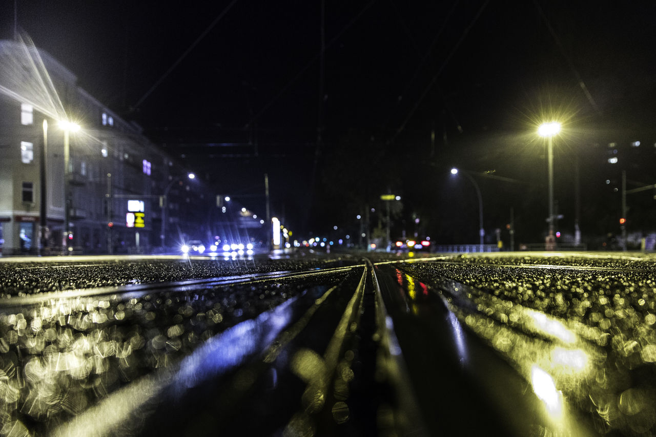 ILLUMINATED RAILROAD TRACKS ON STREET IN CITY