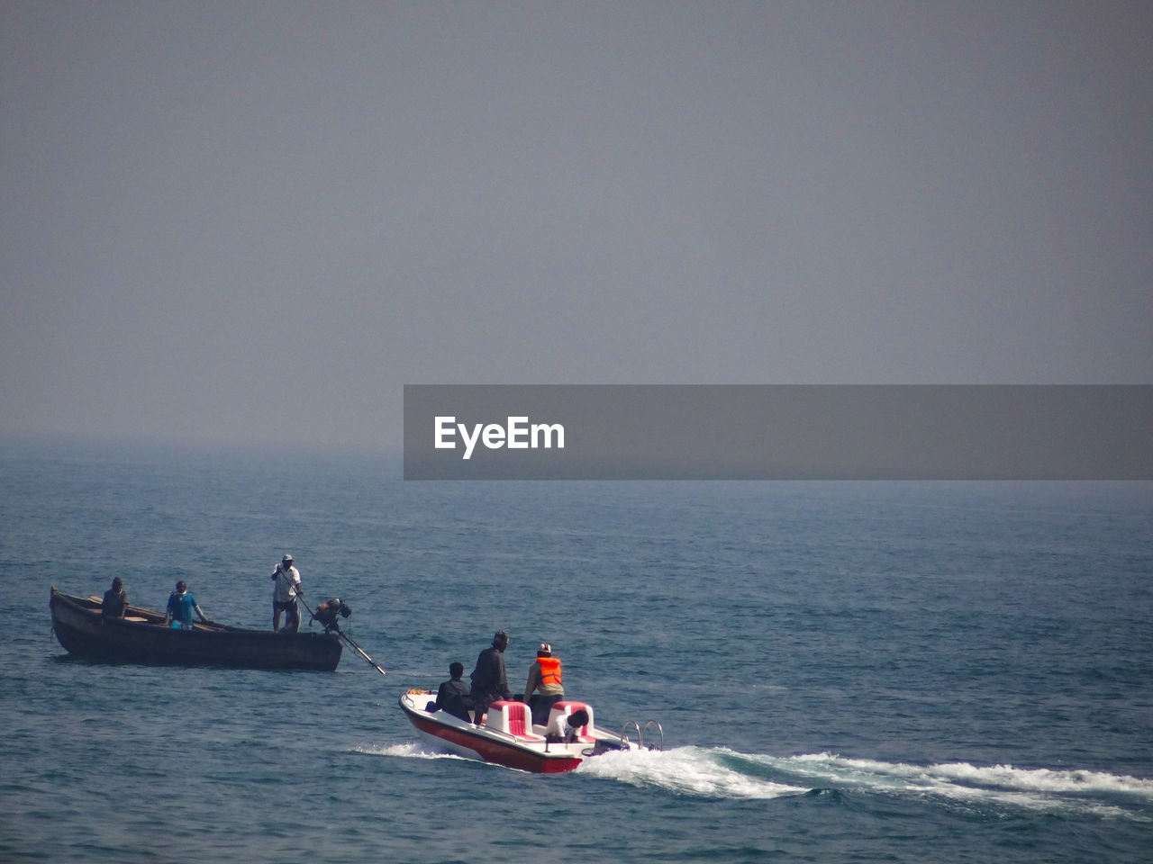 People sailing on boat in sea against sky