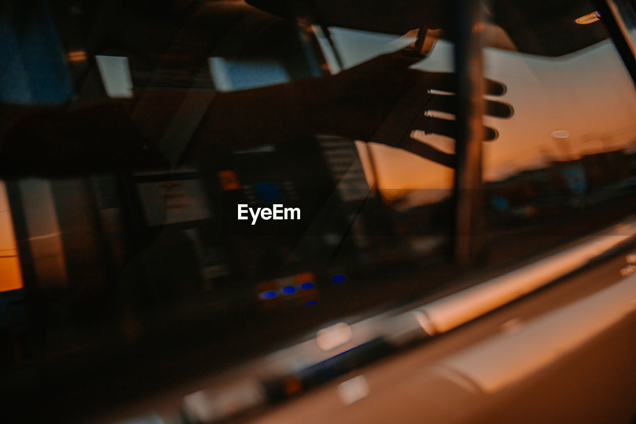 Close-up of hand reflecting on car window