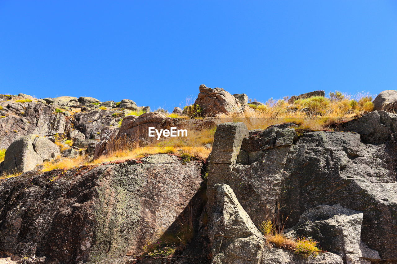 Low angle view of rocks against blue sky