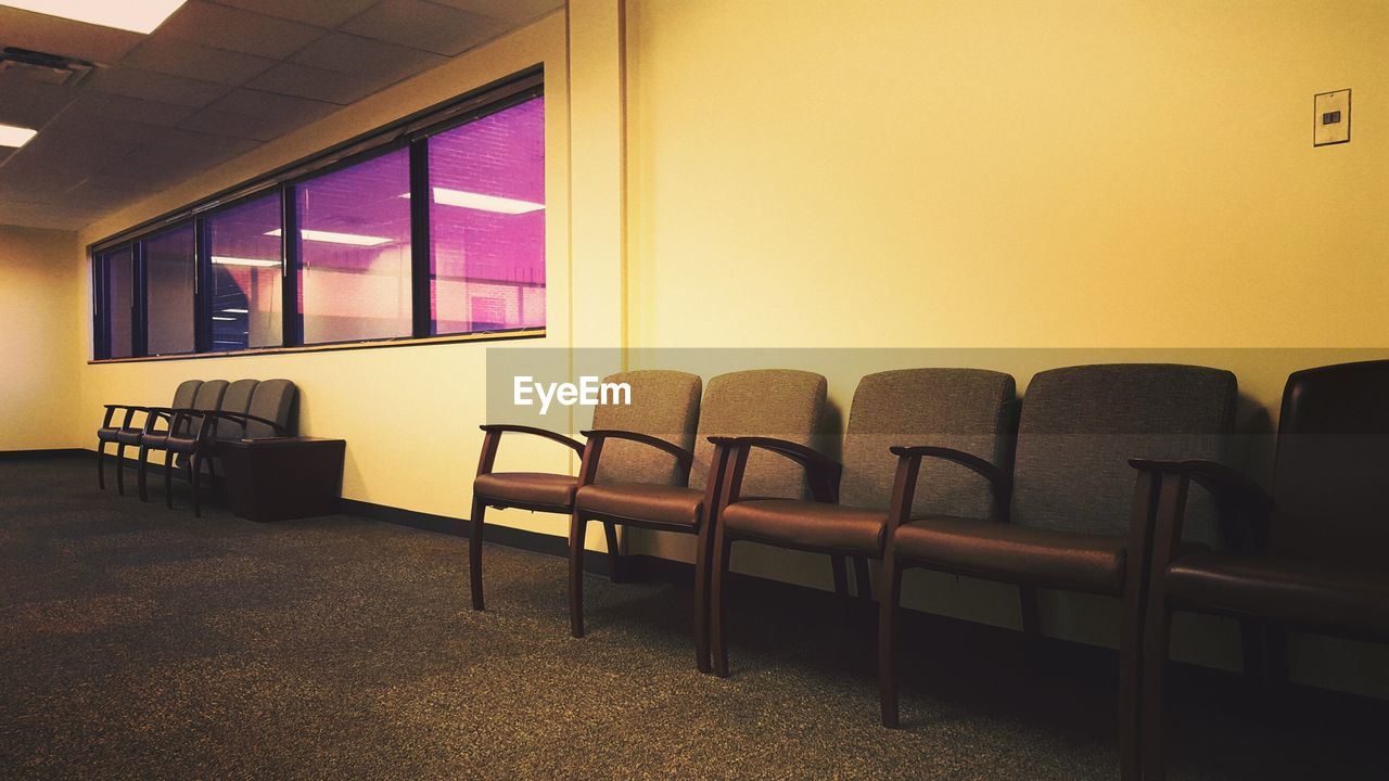 Empty chairs and table against window