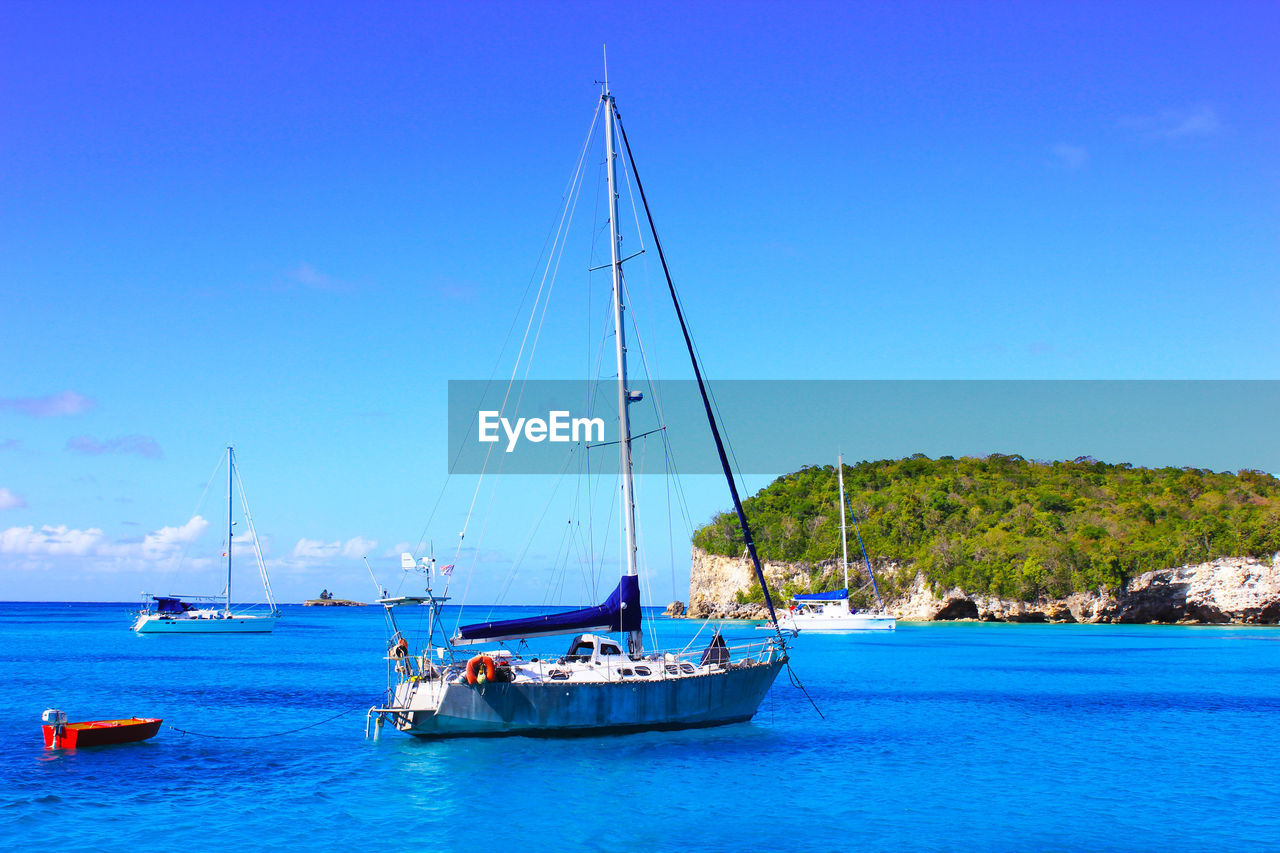 SAILBOAT SAILING IN SEA AGAINST BLUE SKY