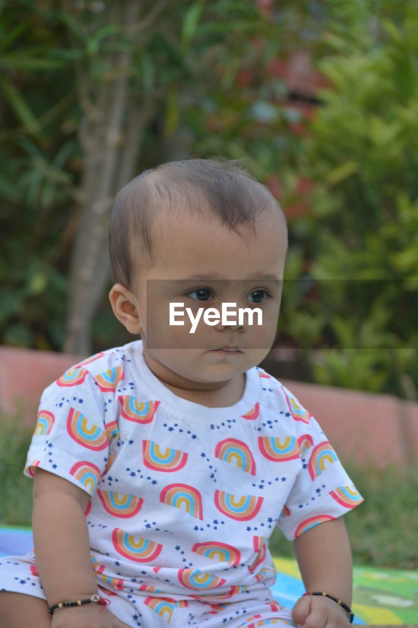 child, childhood, portrait, one person, baby, toddler, baby & toddler clothing, innocence, person, cute, front view, emotion, looking at camera, sitting, nature, day, outdoors, lifestyles, smiling, baby clothing, casual clothing, focus on foreground, waist up, facial expression, looking, three quarter length, happiness, clothing, serious, human face, skin, eye