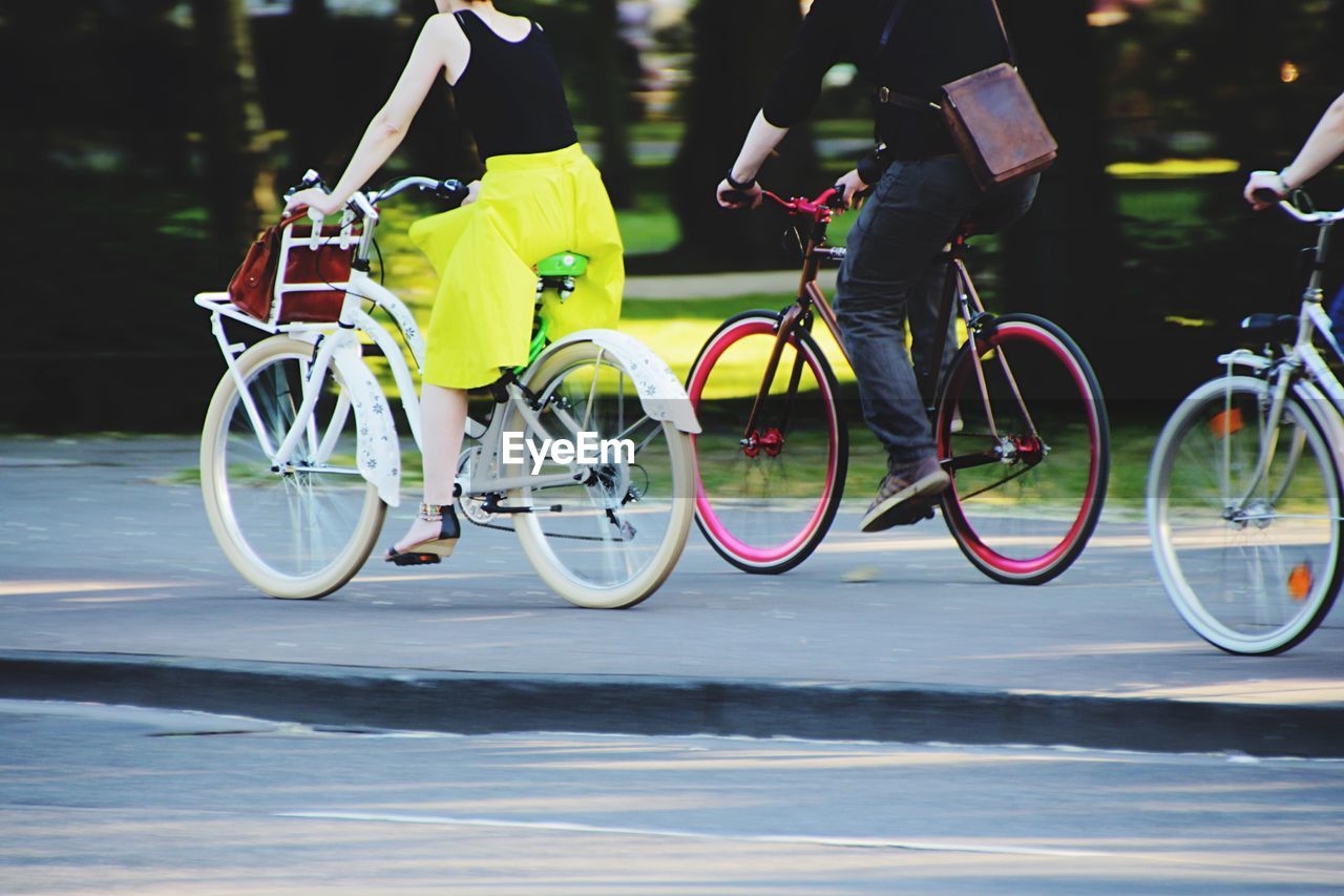 Low section of man and woman riding bicycle on street