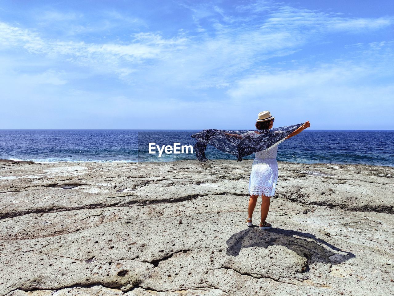 Rear view of woman standing at beach against sky