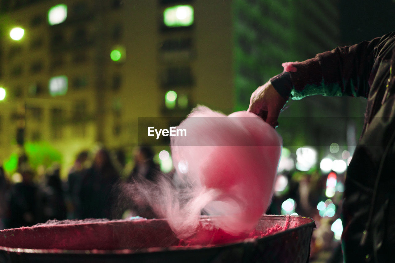 Cropped hand of man preparing pink cotton candy