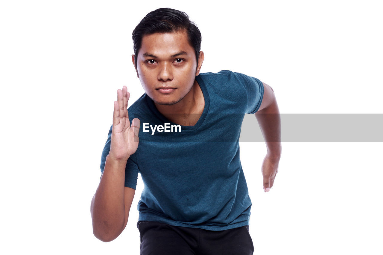 Portrait of young man jogging against white background