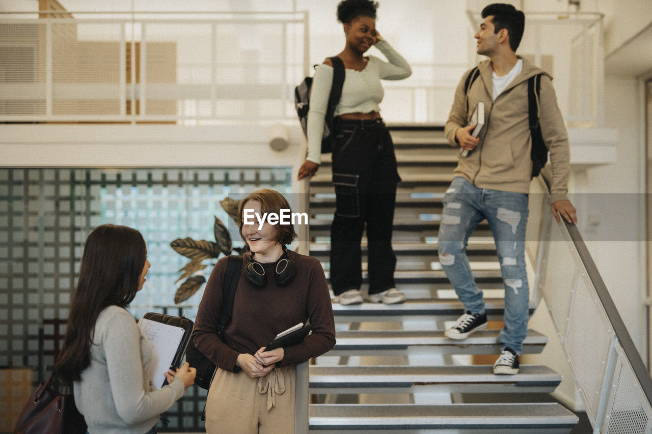 Multiracial male and female students with backpacks talking in university