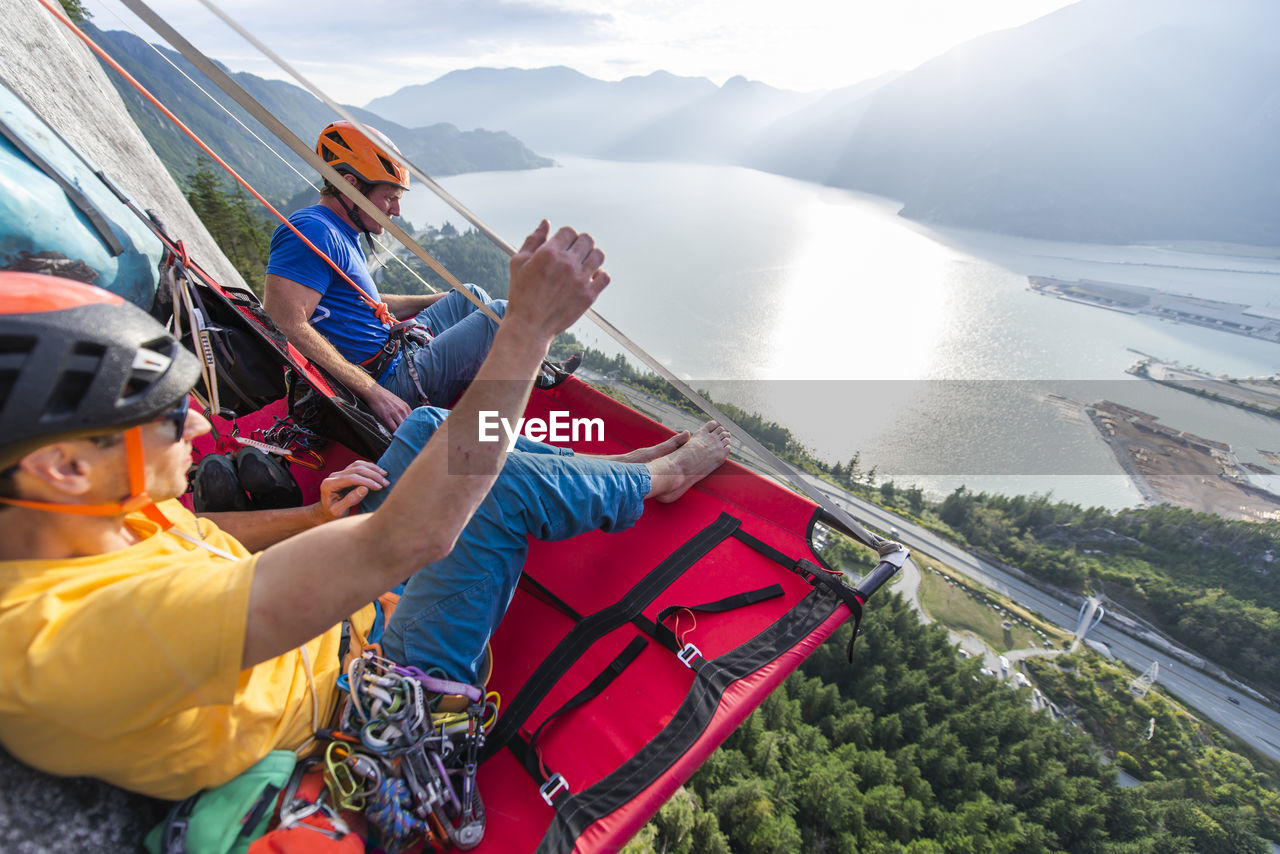 Two men sitting on a portaledge enjoying sunset and view in squamish
