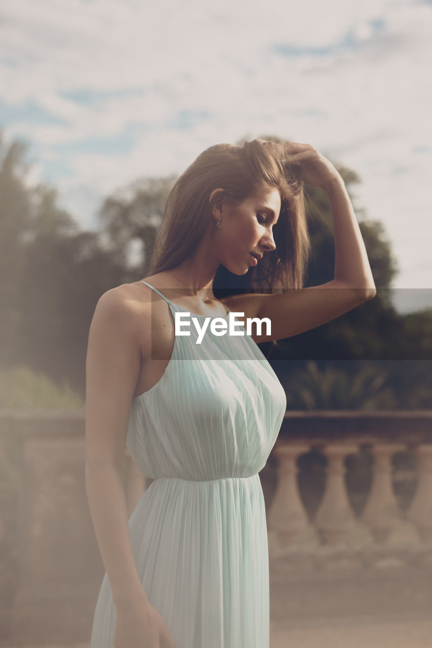 Young woman standing against sky