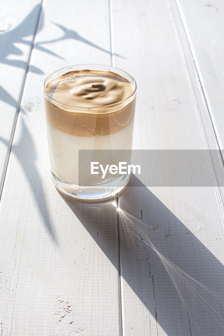 Traditional korean drink, dalgona coffee in a transparent glass on a white board background.