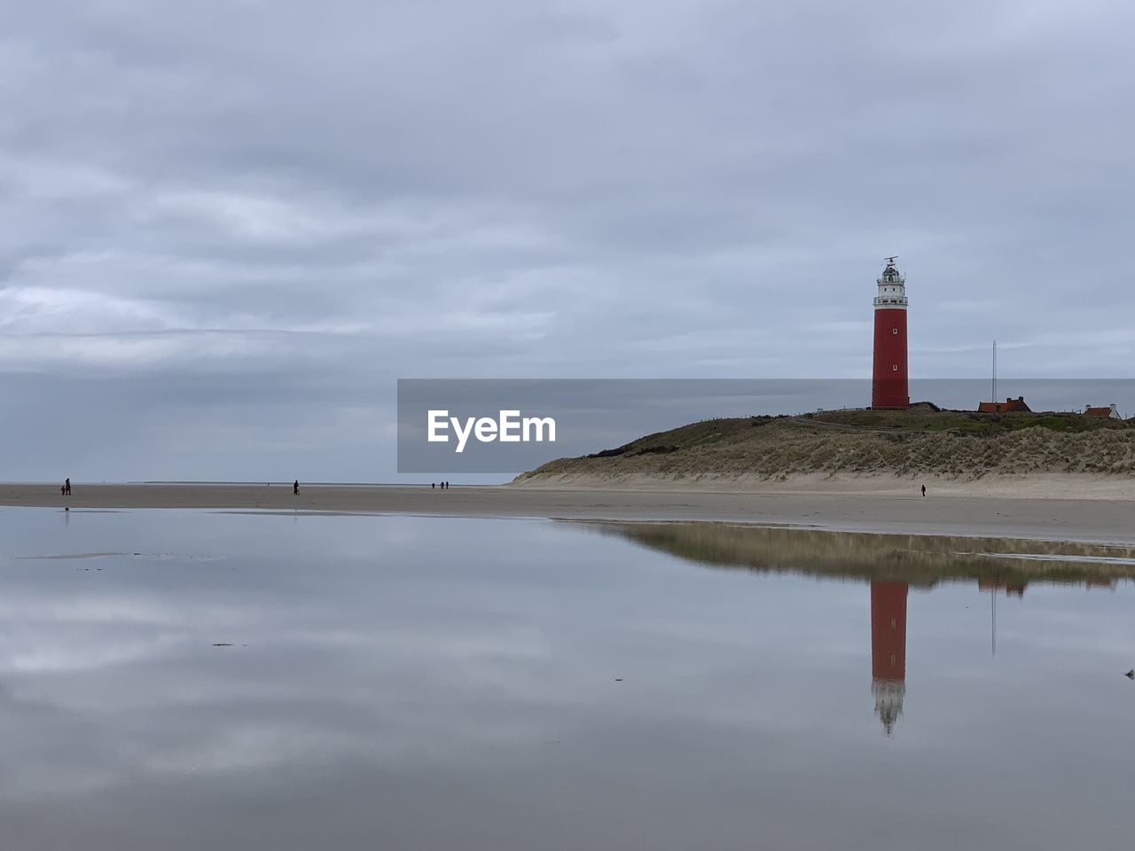 Lighthouse by building against sky