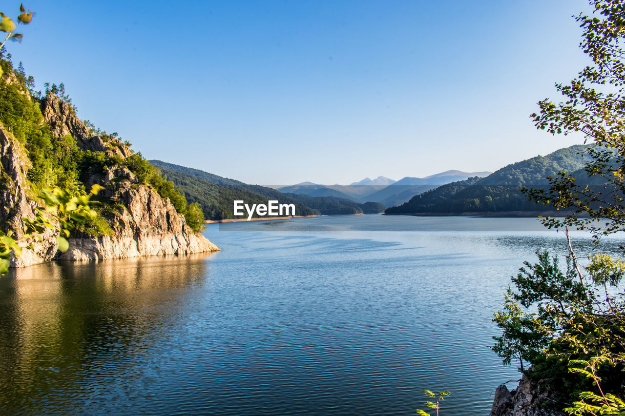 Scenic view of lake against clear blue sky