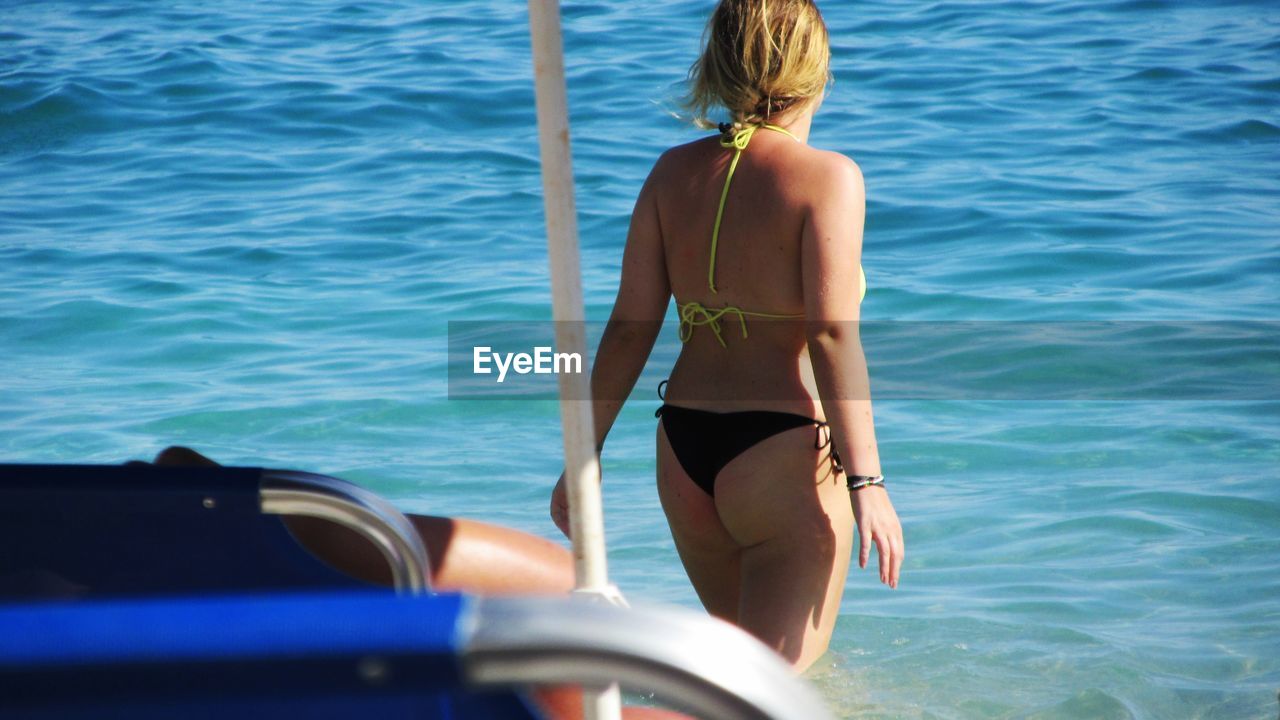 REAR VIEW OF PEOPLE IN FRONT OF BOATS IN SEA