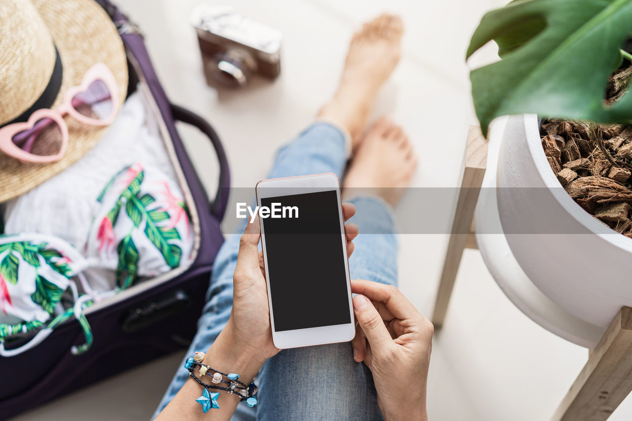 MIDSECTION OF WOMAN USING MOBILE PHONE IN MIRROR