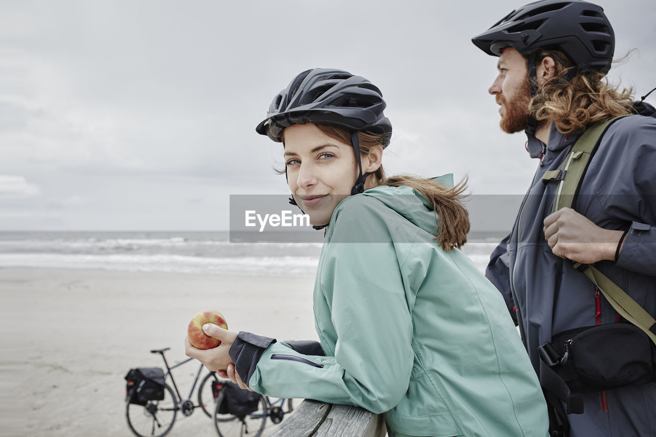 Germany, schleswig-holstein, st peter-ording, couple on a bicycle trip having a break on jetty at the beach