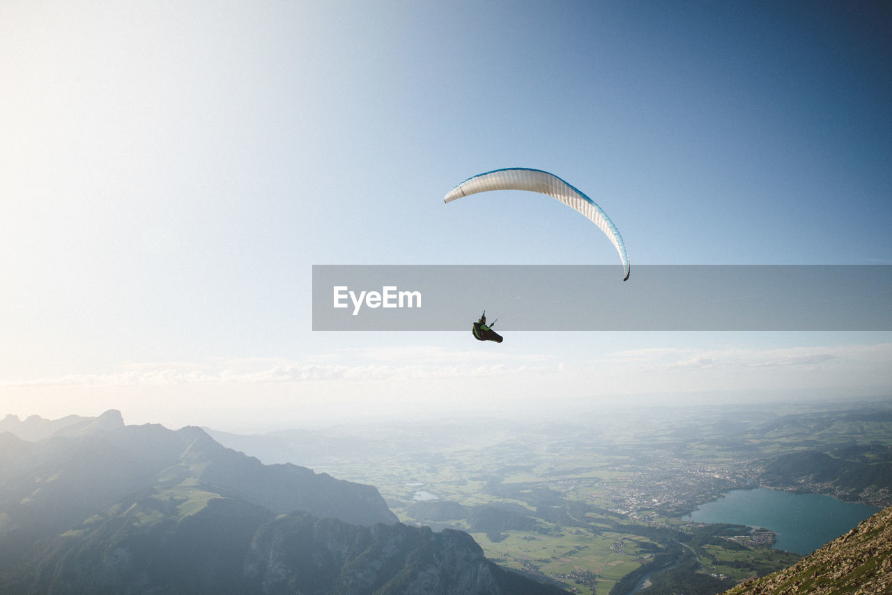 Man paragliding over mountains against sky