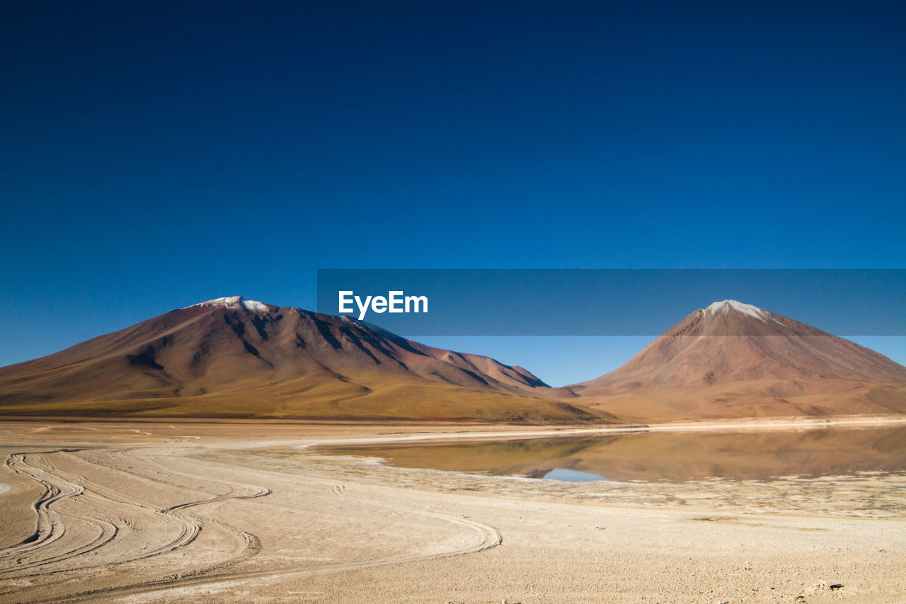 Scenic view of desert against clear blue sky