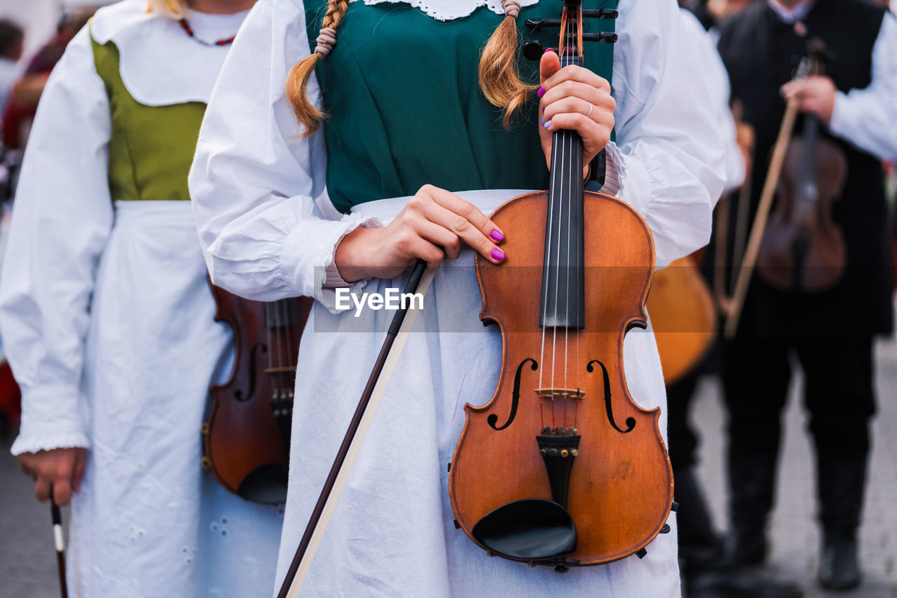 Violin held in hand by a woman in traditional clothes in poland during a festival.