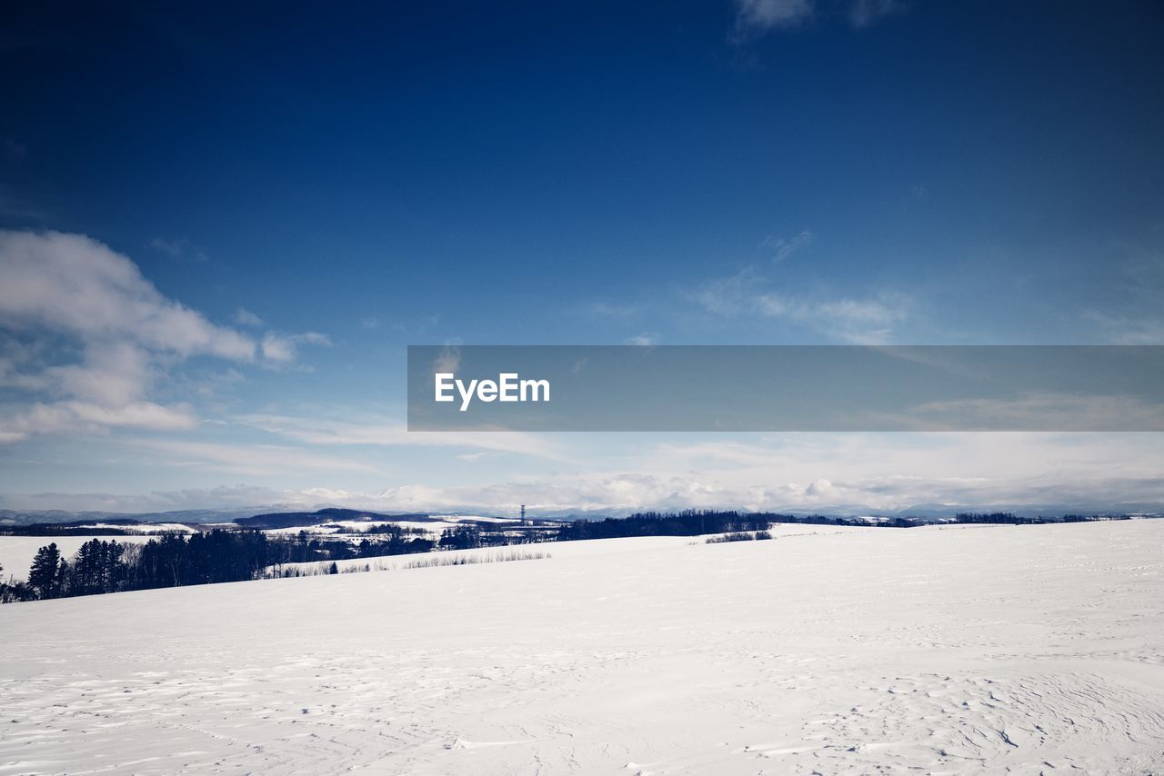 Snow covered landscape against blue sky