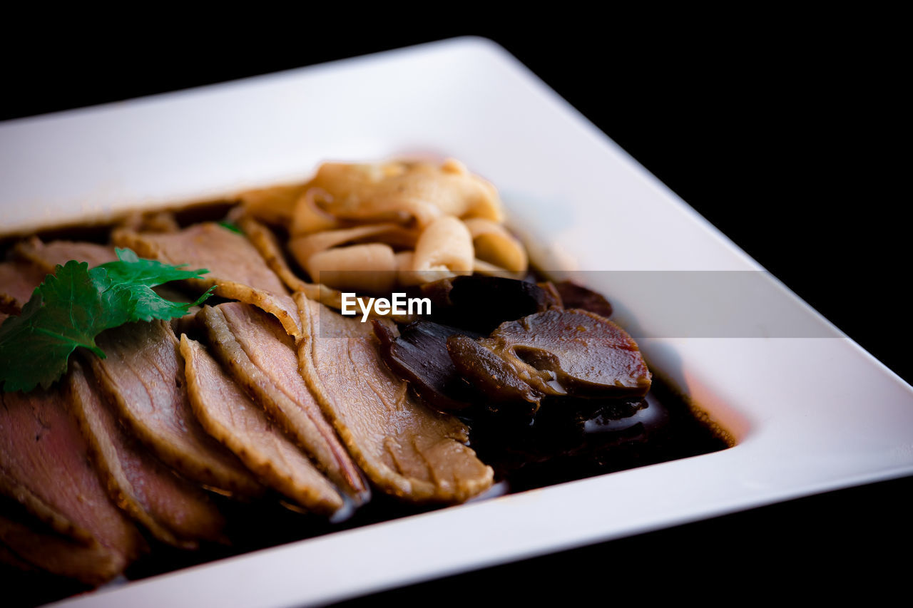 Close-up of meat in plate on black background