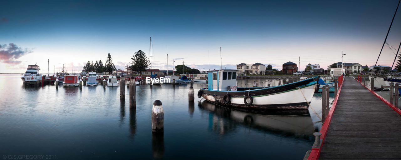 BOATS MOORED IN HARBOR AGAINST SKY