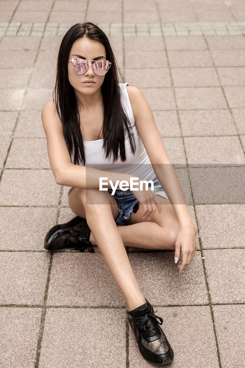 Young woman sitting on walkway