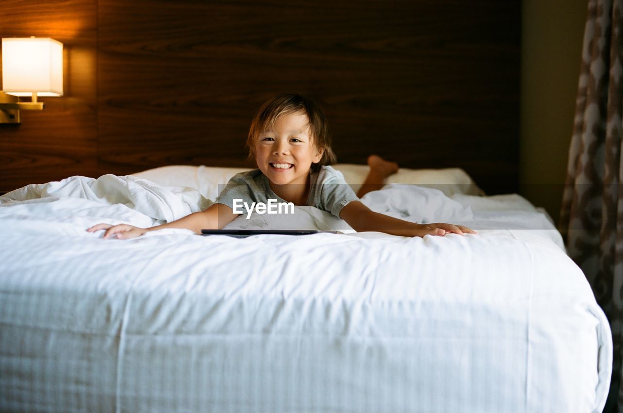 Portrait of a smiling boy lying on bed