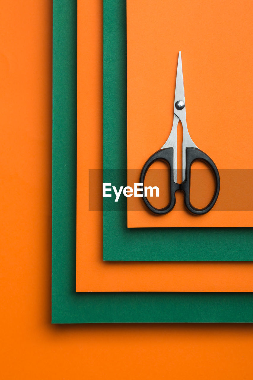 Scissors on green and orange cardboard background