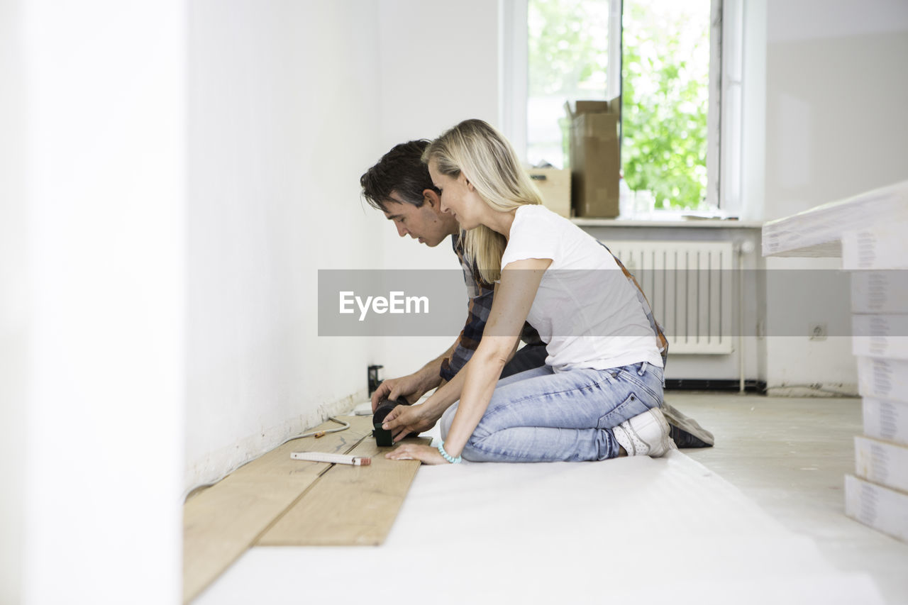 Side view of couple doing carpentry work at home