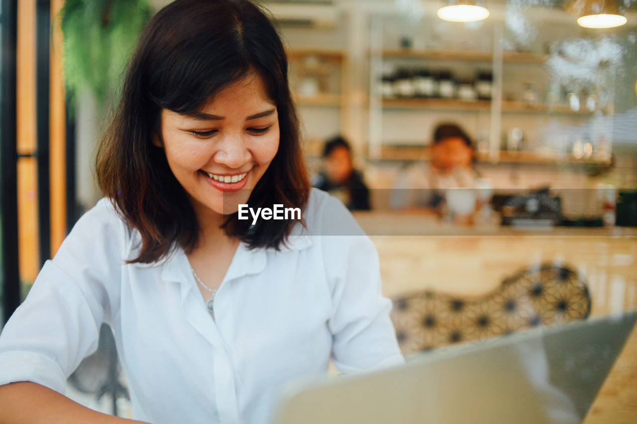 Smiling businesswoman using laptop in cafe