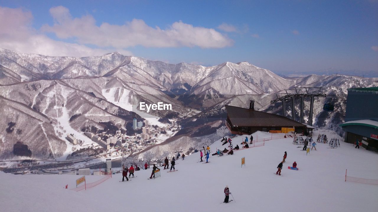 Scenic view of snow covered field and mountains against cloudy sky