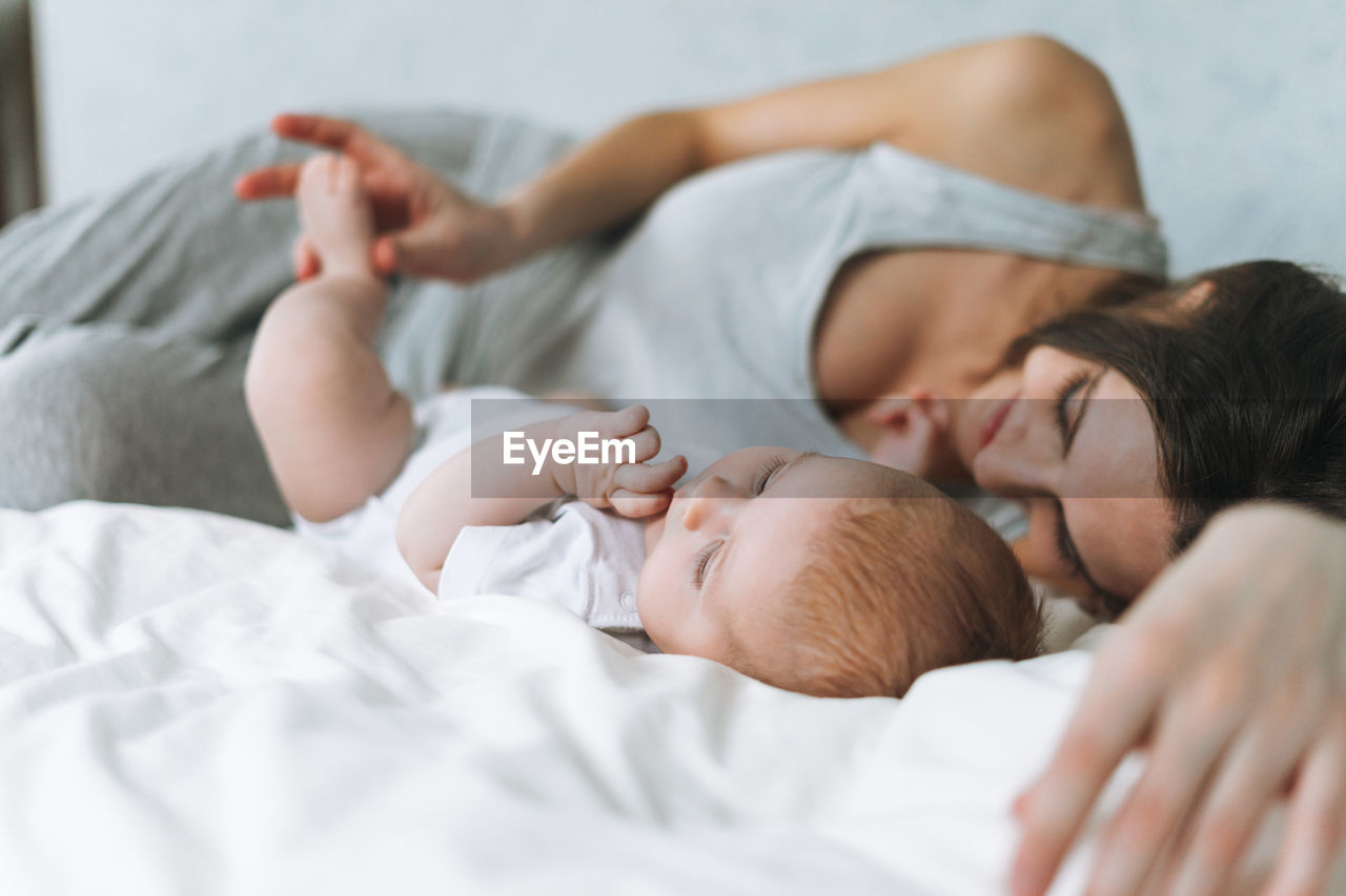 Young mother having fun with cute baby girl on bed, natural tones, love emotion, selective focus