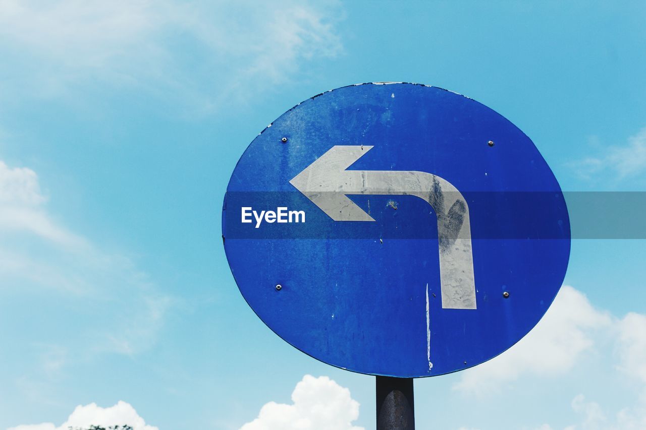 Low angle view of road sign against blue sky