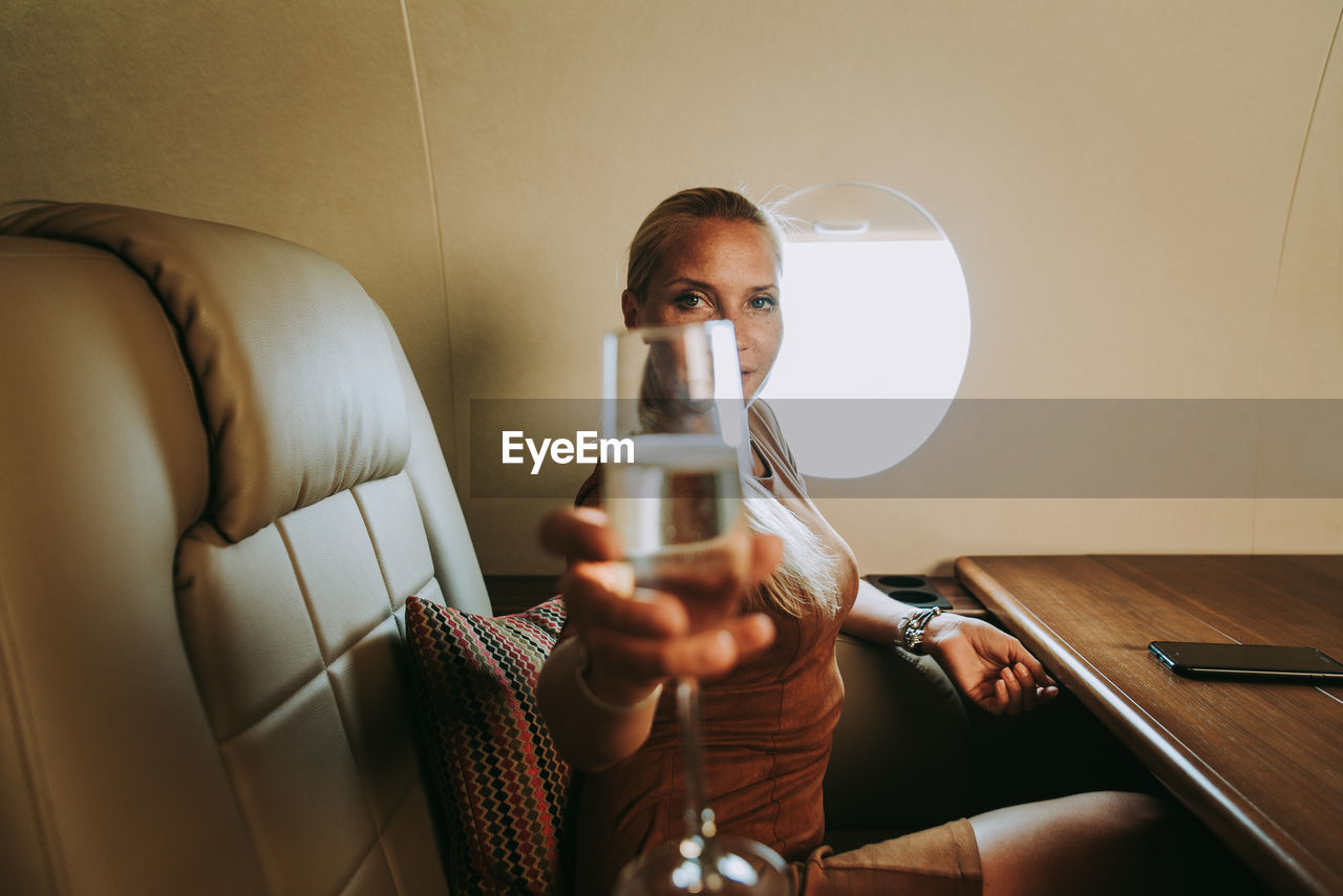 Portrait of businesswoman holding wineglass in airplane