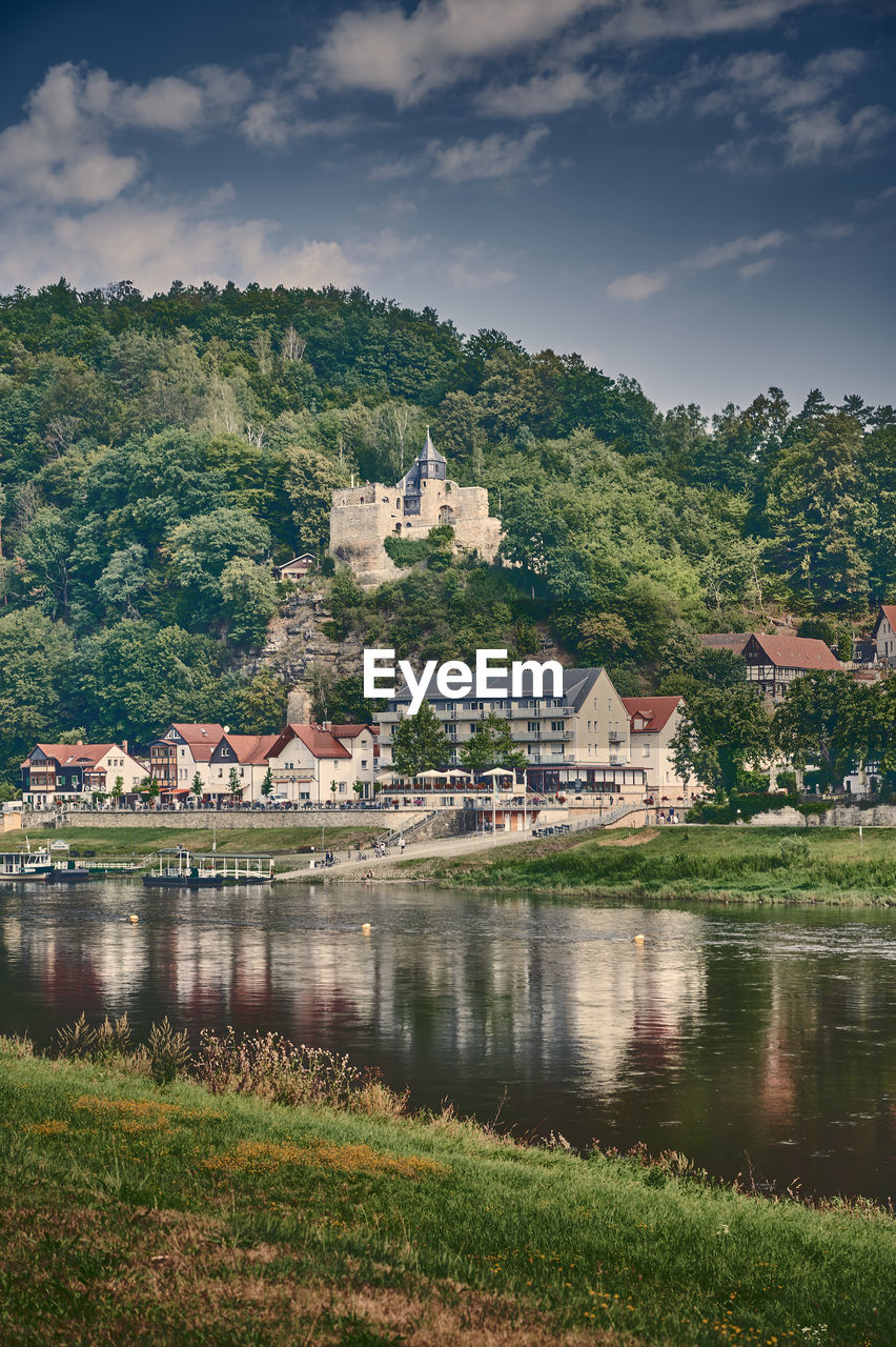 Buildings by river against sky