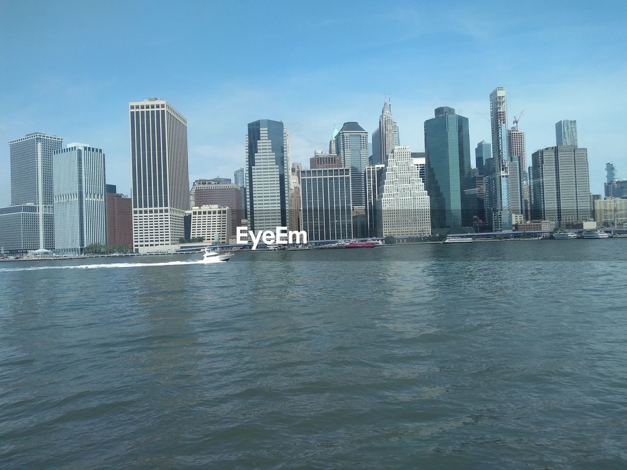 Modern buildings by sea against sky in city