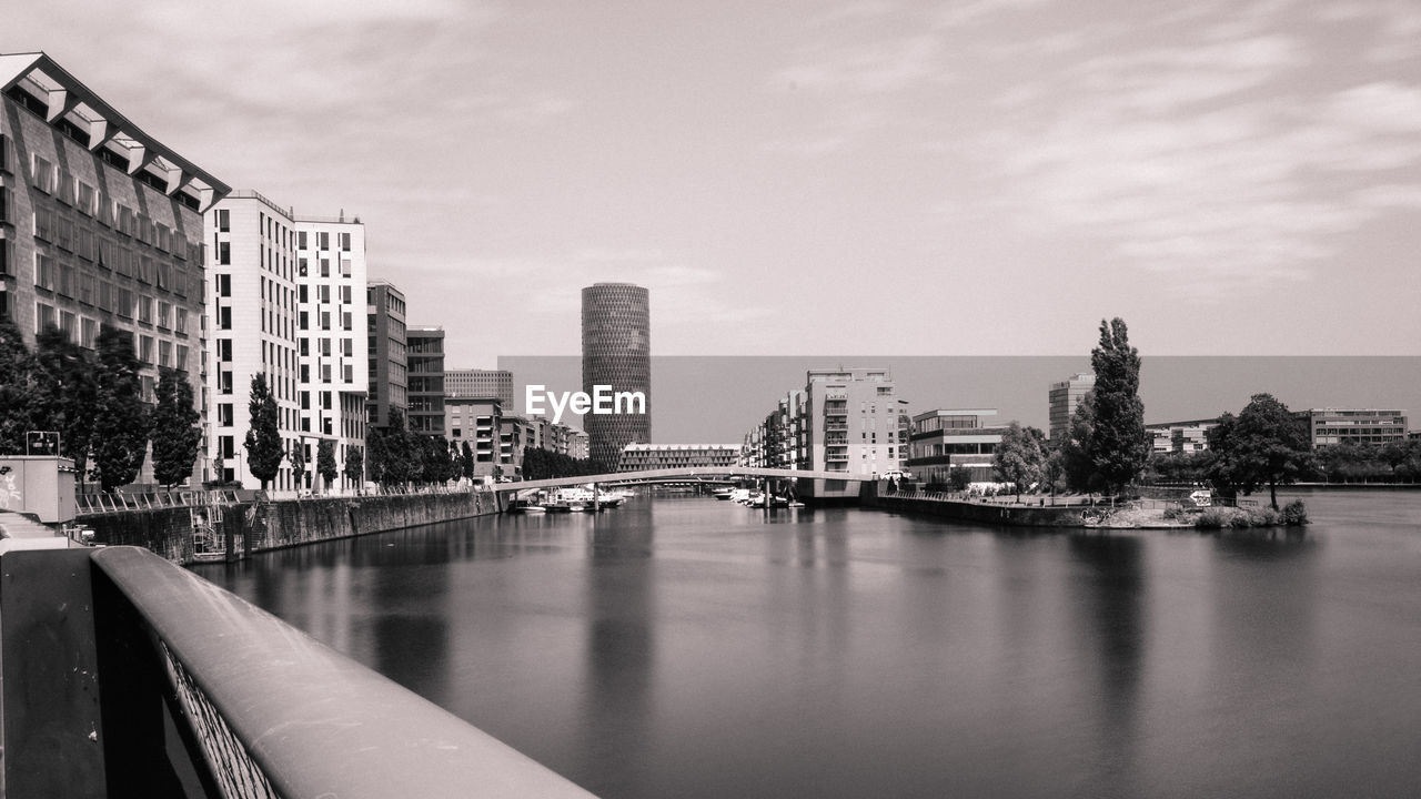 River by buildings in city against sky