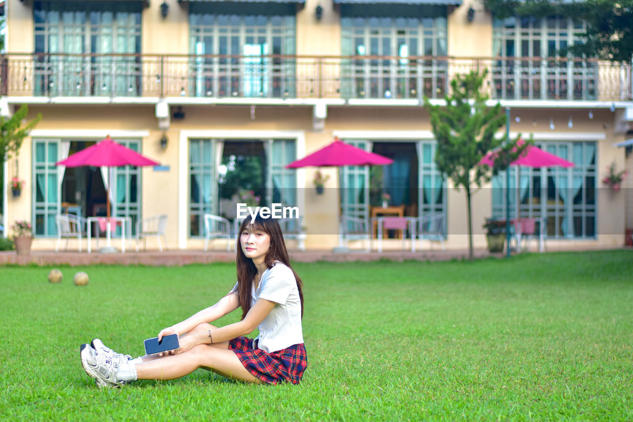 side view of young woman sitting on field