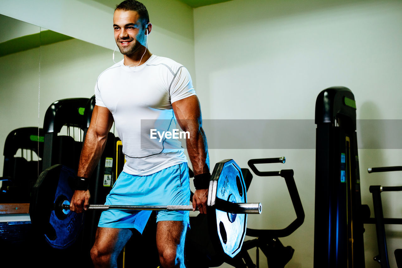 Smiling man lifting dumbbells in gym