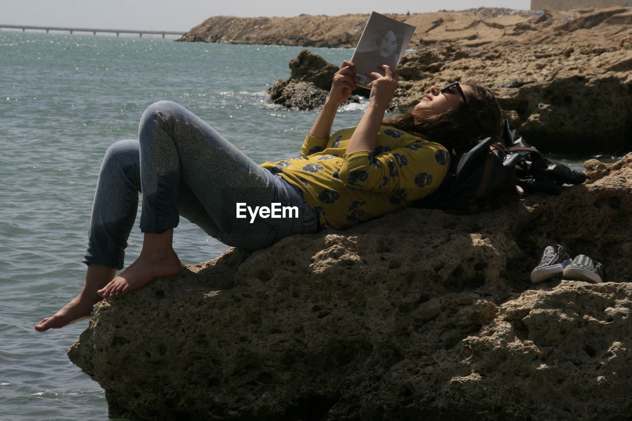 WOMAN RELAXING BY SEA